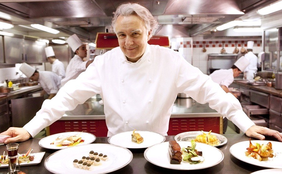 Alain Ducasse (21 Michelin Stars) is standing near the table with a lot of delicious desserts