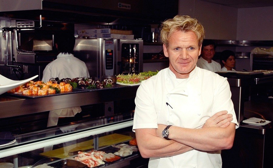 Gordon Ramsay (16 Michelin Stars) is posing in the kitchen while chefs around are preparing food