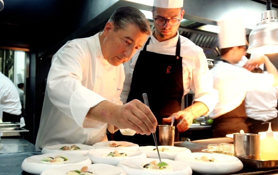 Joan Roca (3 Michelin Stars) is checking a prepared dish while another chef is standing near