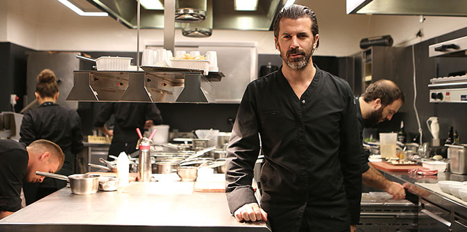 Andreas Caminada (7 Michelin Stars) standing in his restaurant kitchen